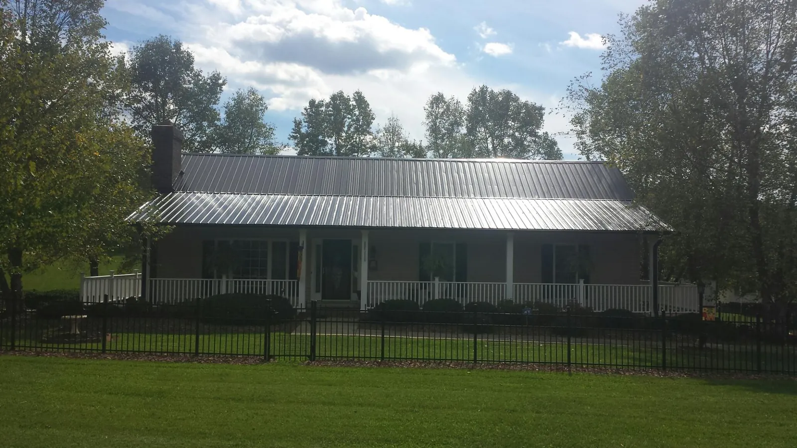 Gray metal roof on a brick ranch with a full width front porch in Rocky Point
