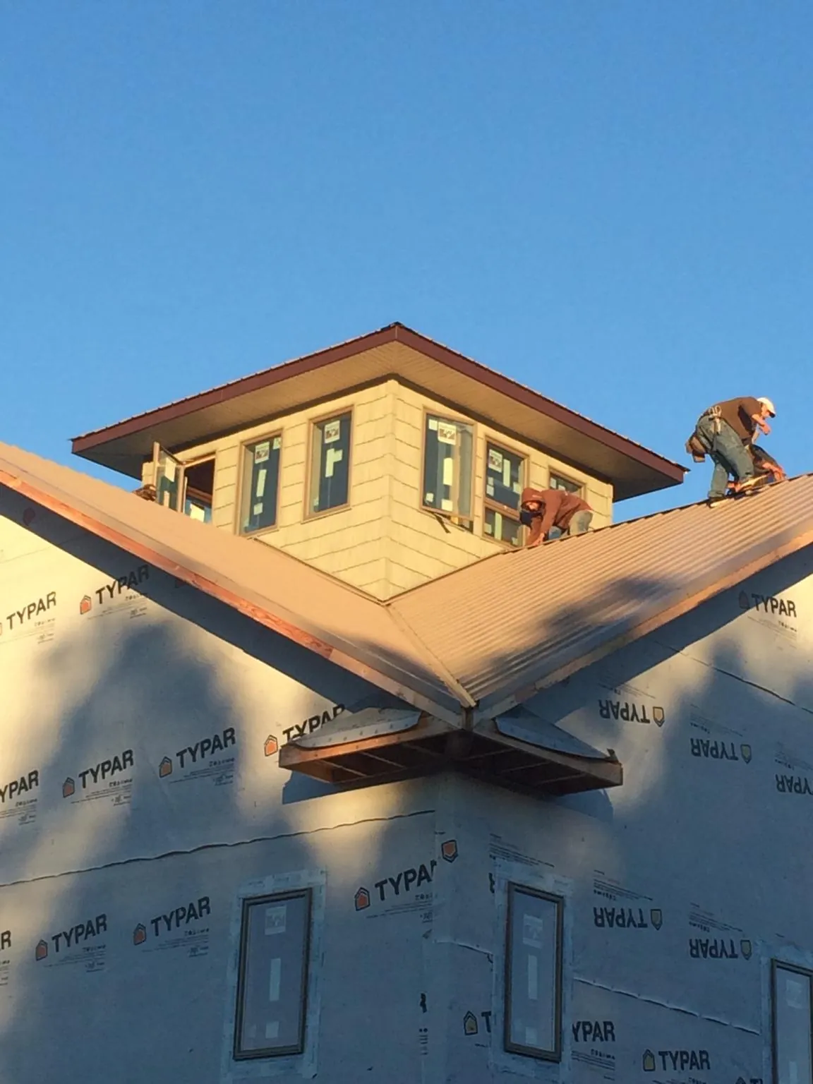 Roofers working around a rooftop cupola on a new metal roof at sunset — Roof Waterproofing in Rocky Point by Roofing Brothers
